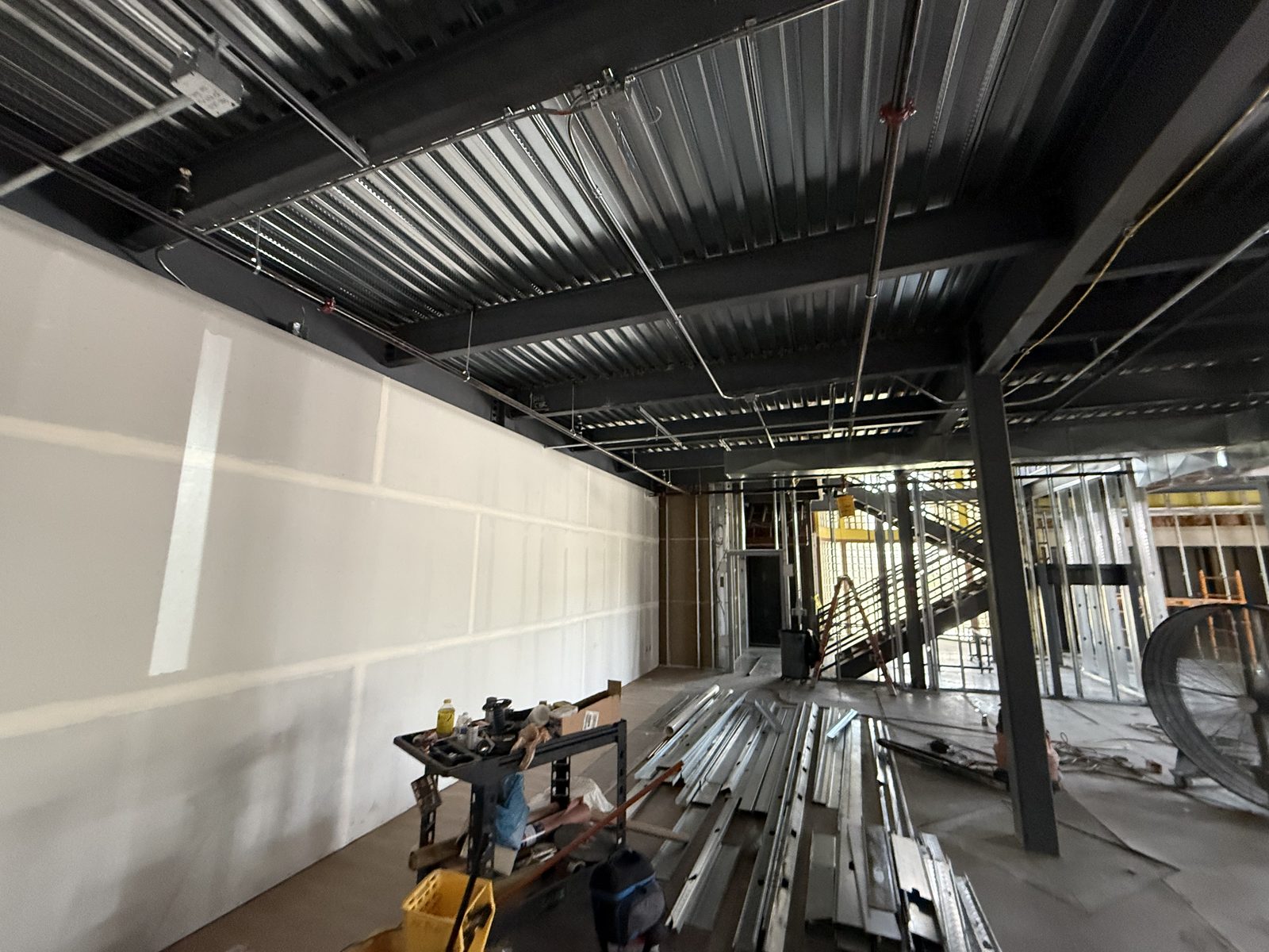 Electrical conduit and EMT routed under the metal roof deck and structural steel beside the stair opening on the CBR commercial build-out by Arizona Electrical Solutions