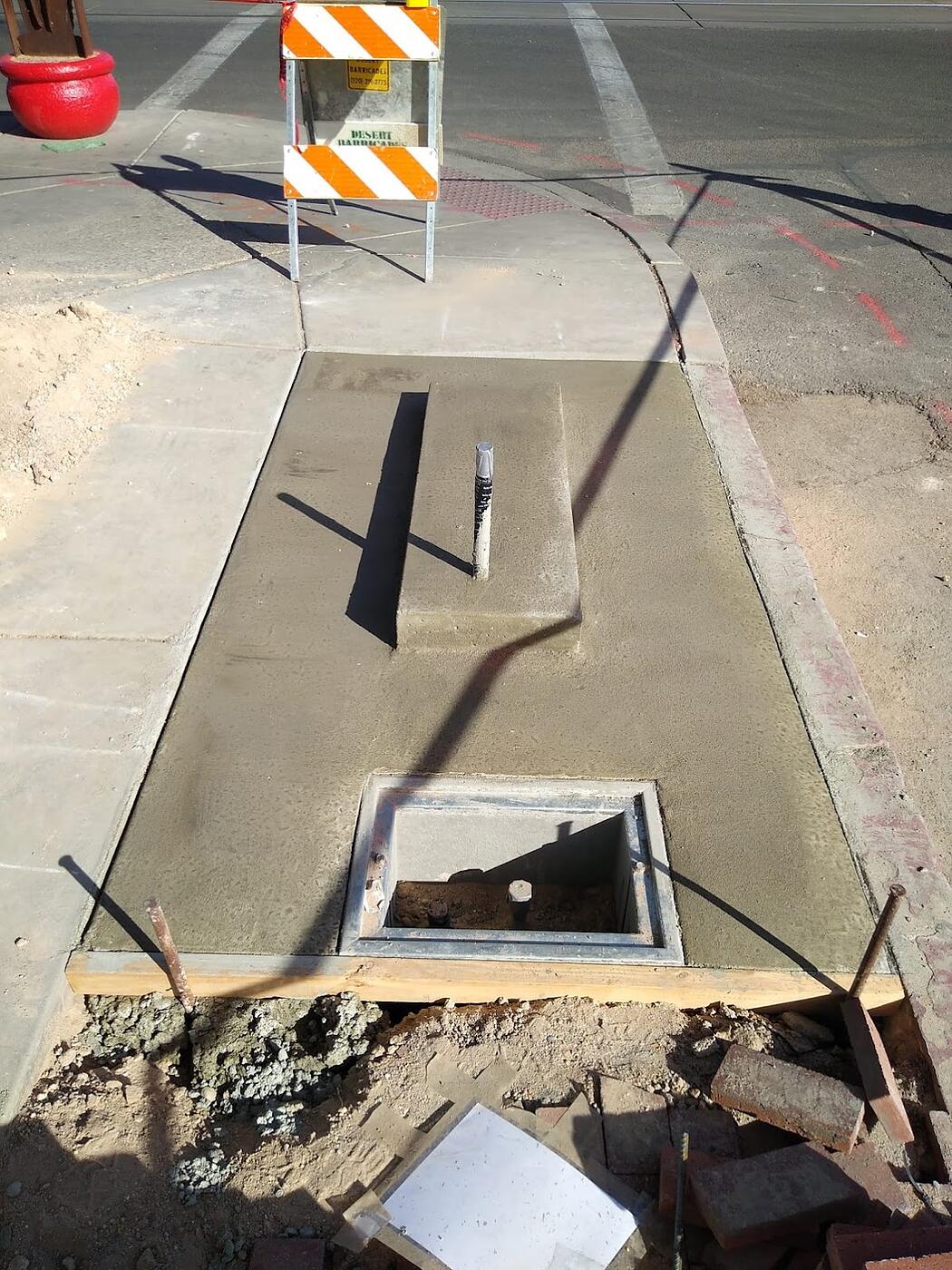 Finished concrete kiosk pad at a corner with cast-in pull box and conduit stub-up, sidewalk restored, Tucson, Arizona