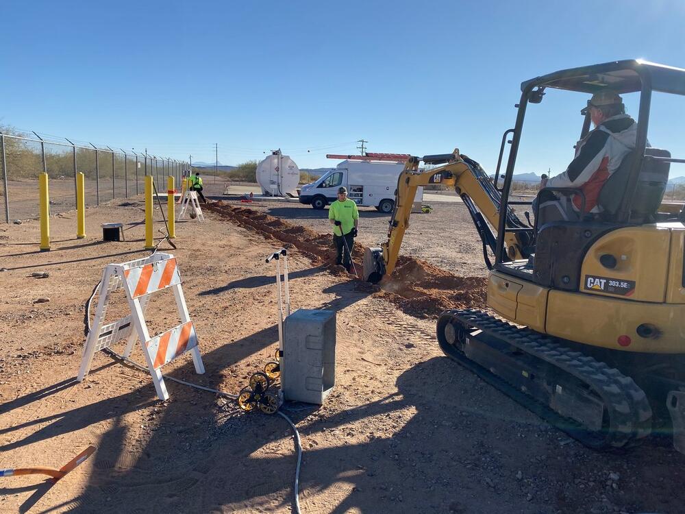 Arizona Electrical Solutions crew trenching for underground electrical with a CAT excavator on a commercial site in the Tucson area